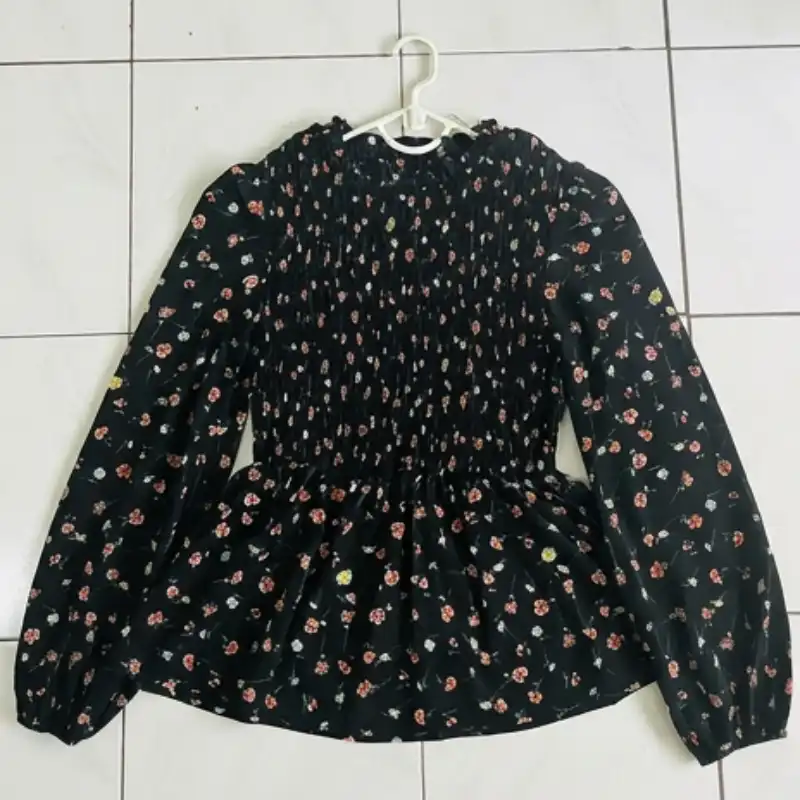 Floral blouse laid flat with a hanger on a tiled floor — shape and drape completely lost