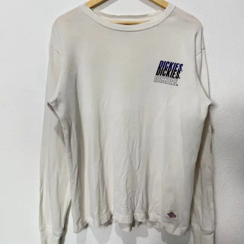 Wrinkled white long-sleeve top on wooden hanger with visible creases