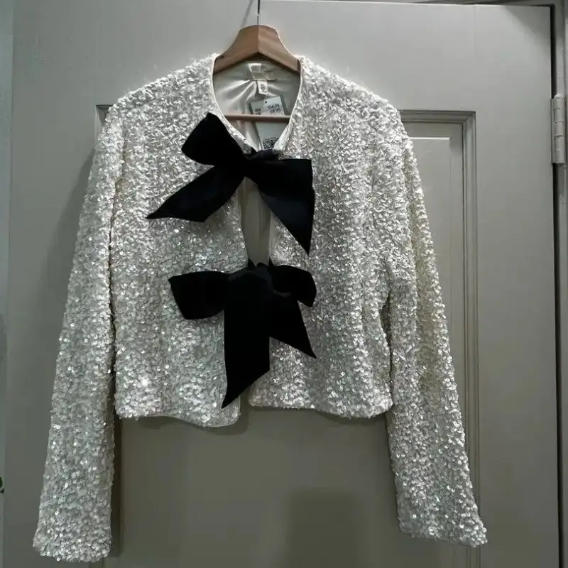 Sequin jacket on hanger photographed against a door with poor lighting